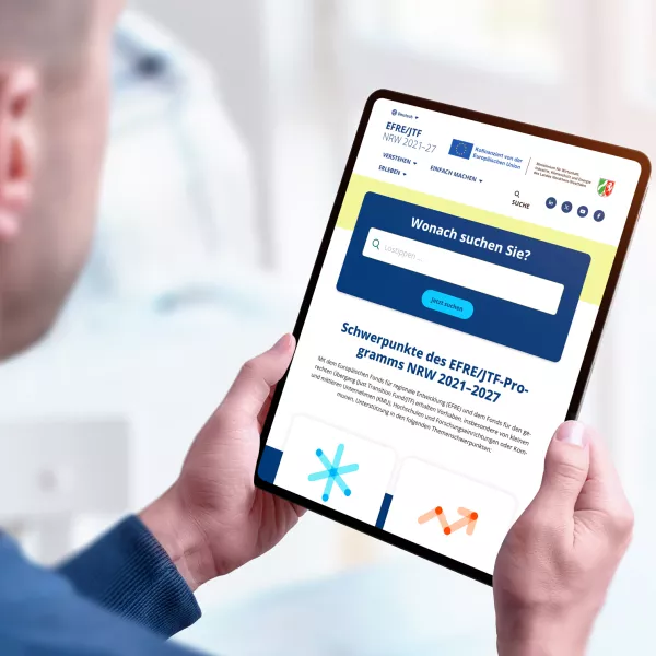 Hero EFRE Ein Mann hält ein Tablet, auf dem die neue Webseite von EFRE zu sehen ist